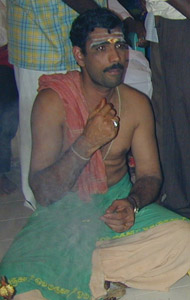 The vibhuti -three lines drawn horizontally across the priest's forehead in white ash- represents Shiva's all pervading nature.